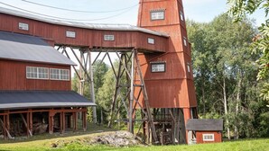 En röd träbyggnad med ett stort torn och ett överbyggt område med ett tak av metall.