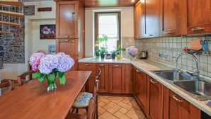 A kitchen with wooden cabinets, a dining table with chairs, a window with plants, and a sink.