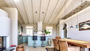 A modern kitchen with a central island, bar stools, and a dining table with chairs. - Villa di Sogno by Interhome (Lacona)