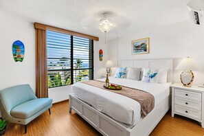 Une chambre d’hôtel comprenant un lit, une chaise, une table de chevet, une lampe, une fenêtre avec des stores et une vue sur l’extérieur.