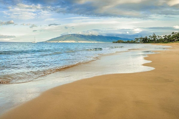 Ein Strand mit freiem Blick auf das Meer und einem entfernten Berg.