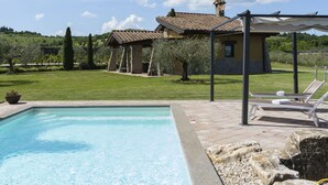 A pool area with a clear blue pool, lounge chairs, and a pergola. - Cipresso by Interhome (Lago di Vico)