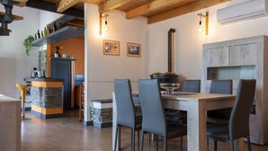 A modern kitchen with a dining area, featuring a wooden ceiling, stone accents, and a built-in stove. - Cipresso by Interhome (Lago di Vico)