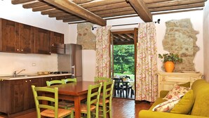 A cozy kitchen with wooden cabinets and a dining area with green chairs. - Le Cascatelle by Interhome (Massa Marittima)