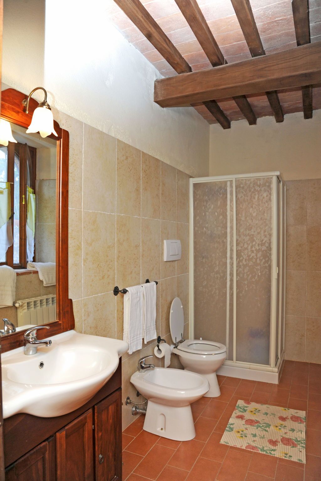 A bathroom with a sink, two toilets, a shower, and a mirror.