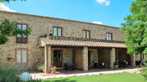 A stone building with a covered patio area, outdoor seating, and potted plants. - Le Cascatelle by Interhome (Massa Marittima)
