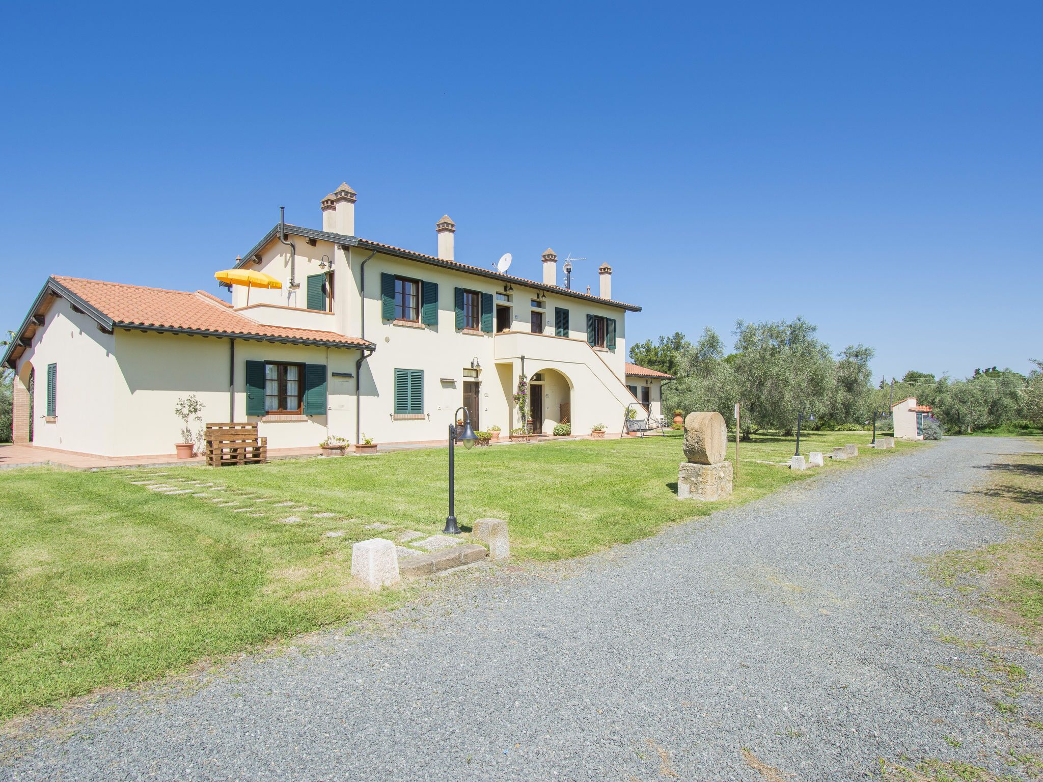 A large, two-story house with a tiled roof, a paved driveway, and a well-maintained lawn.