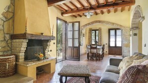 Una sala de estar acogedora con chimenea de piedra, un reposapiés tejido y un sofá con cojines estampados.