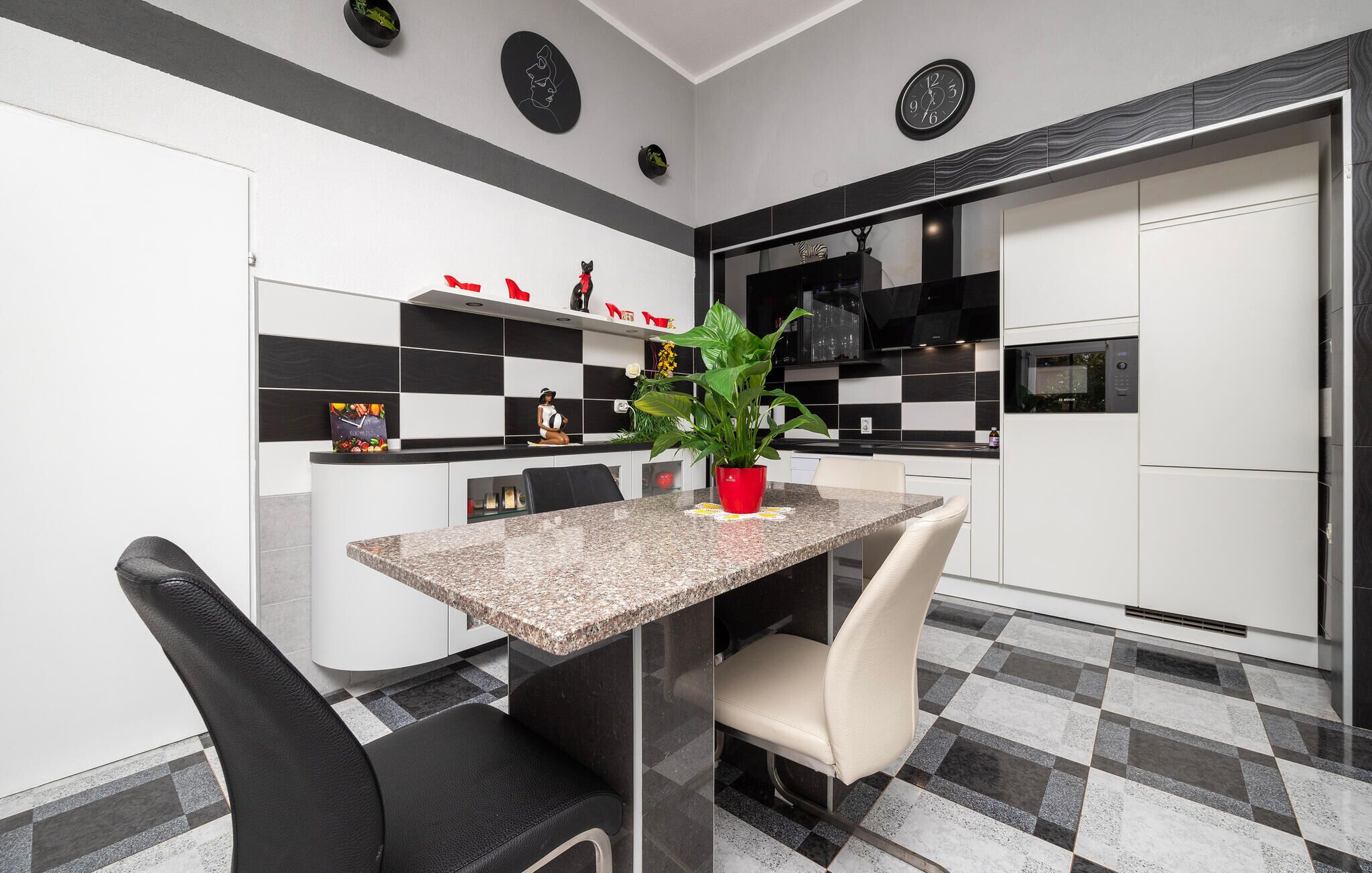 Cozinha moderna com piso xadrez, bancada de granito e área de refeições com duas cadeiras.