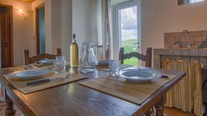 A dining table set with plates, glasses, and a bottle, with a view of greenery outside. - La Fonte by Interhome (Dicomano)
