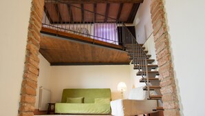 A bedroom with a green bed, a white chair, and a staircase leading to an upper level. - La Fonte by Interhome (Dicomano)