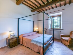 Une chambre à coucher avec un lit à baldaquin, une armoire en bois, une chaise et une fenêtre donnant sur un paysage verdoyant.