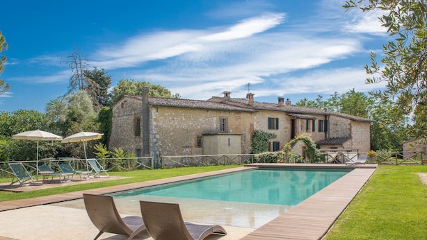 A pool area with lounge chairs, a stone building, and a clear sky. - Podere Fontemaggio - Fienile by Interhome (Colle Val d'Elsa)