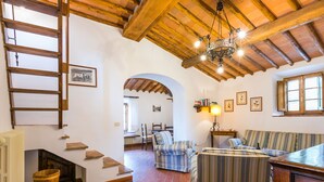 A rustic interior with a wooden staircase, a striped sofa, and a chandelier. - Cellole - Torretta (CTC153) by Interhome (Castellina in Chianti)