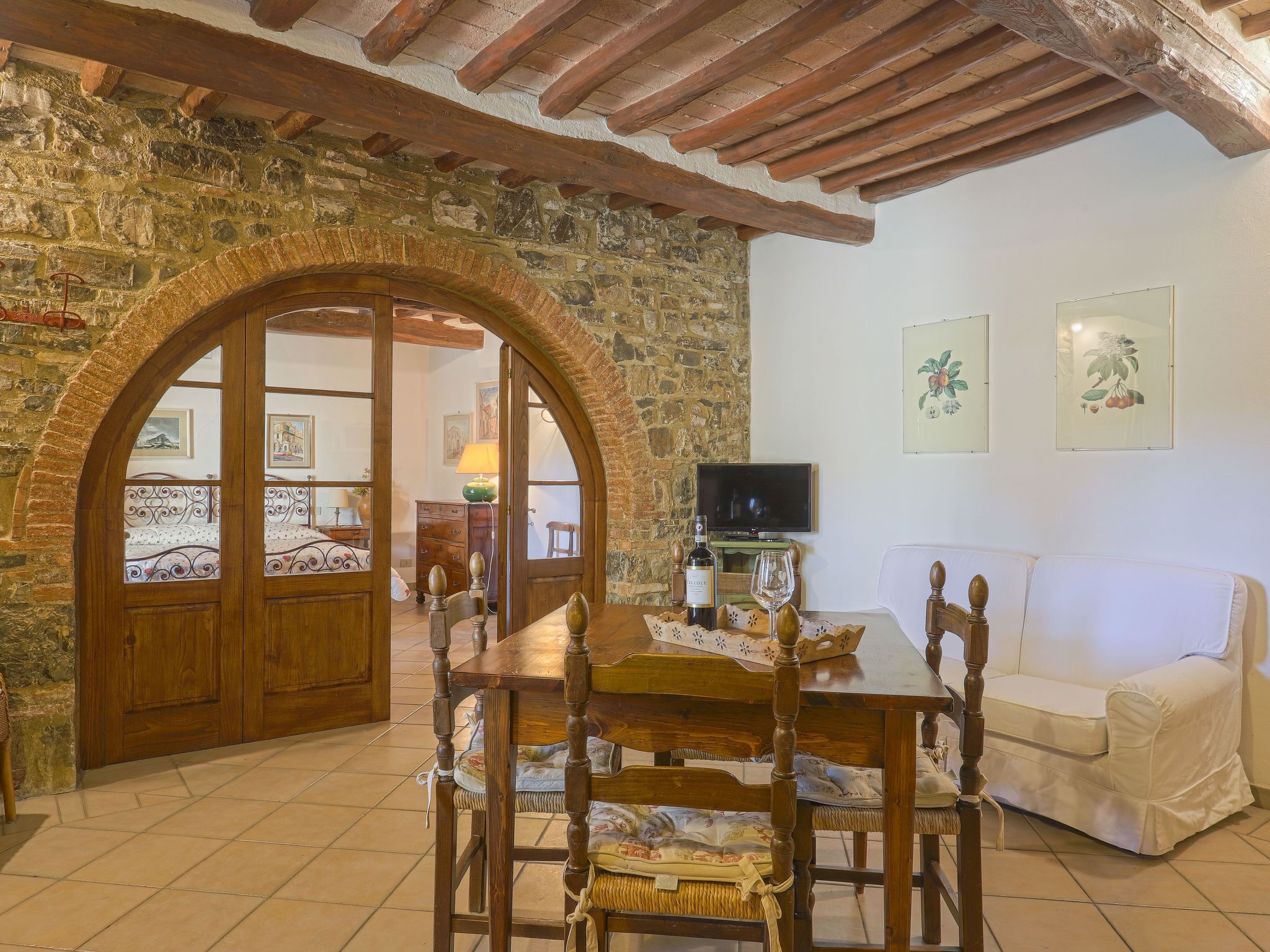 A cozy room with a stone wall, wooden door, and a dining table with chairs.