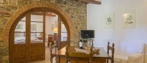 A cozy room with a stone wall, wooden door, and a dining table with chairs.