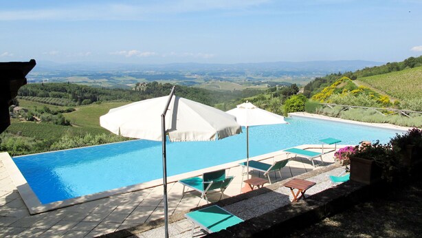 A swimming pool with lounge chairs and umbrellas, surrounded by a scenic landscape. - Cellole - Cellole 1 (CTC150) by Interhome (Castellina in Chianti)