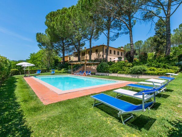 A swimming pool with blue lounge chairs and a pergola.