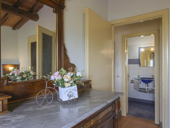 Une salle de bain avec un comptoir en marbre, un miroir, un lavabo avec un receveur bleu et un sol carrelé.