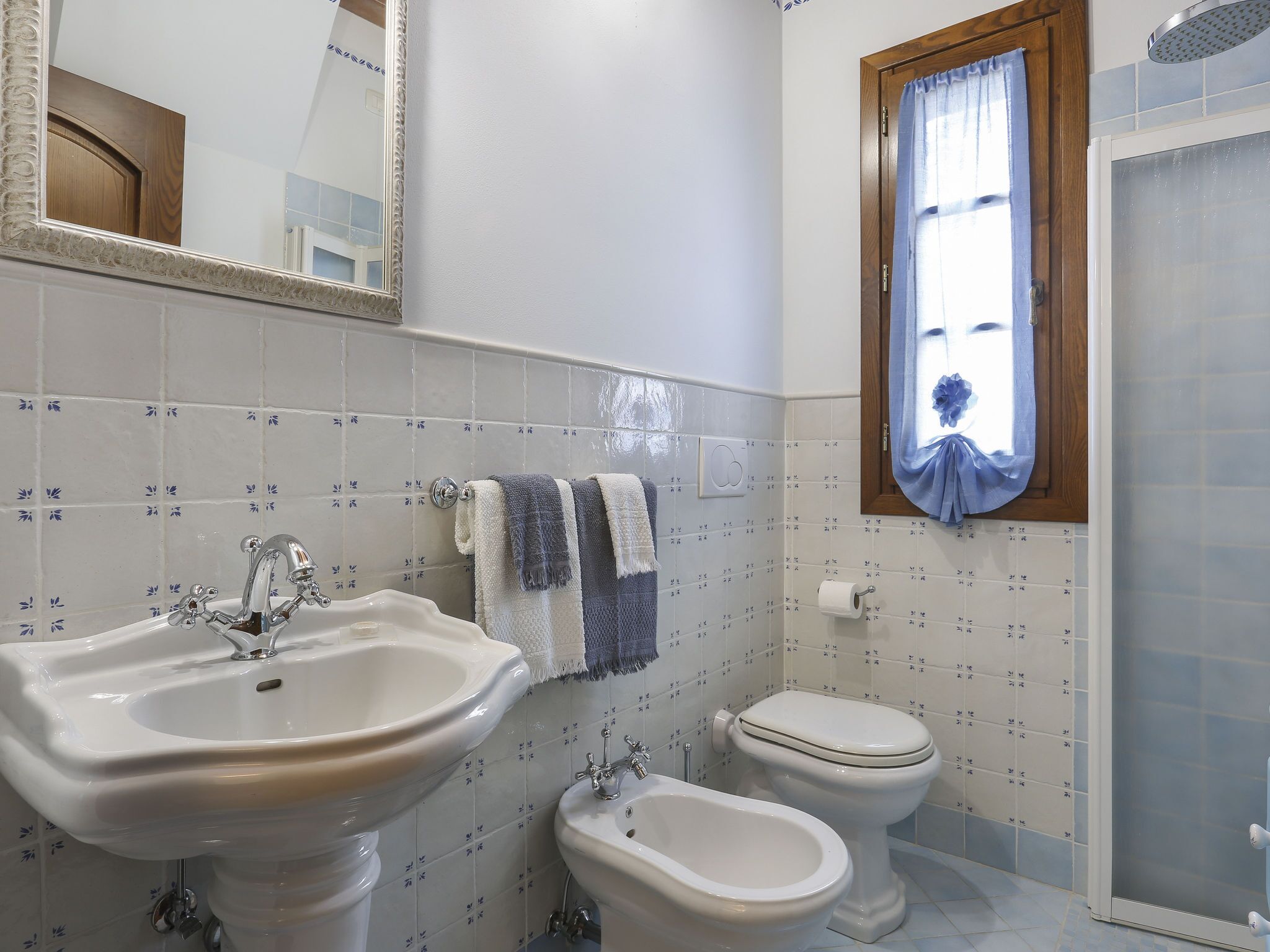 A bathroom with a sink, bidet, toilet, and a mirror.