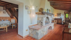 A rustic interior with a stone fireplace, wooden beams, and a dining area with a table and chairs. - La Grotta by Interhome (Camaiore)