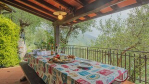 An outdoor dining area with a table set for two, surrounded by greenery and a view of hills. - La Grotta by Interhome (Camaiore)
