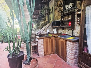 A kitchen with a stone wall, a sink, and a wooden cabinet. - Capo Corso by Interhome (Corsanico)