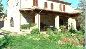 A stone building with a covered porch, arched windows, and a small garden in front. - Castagno by Interhome (Pastina)