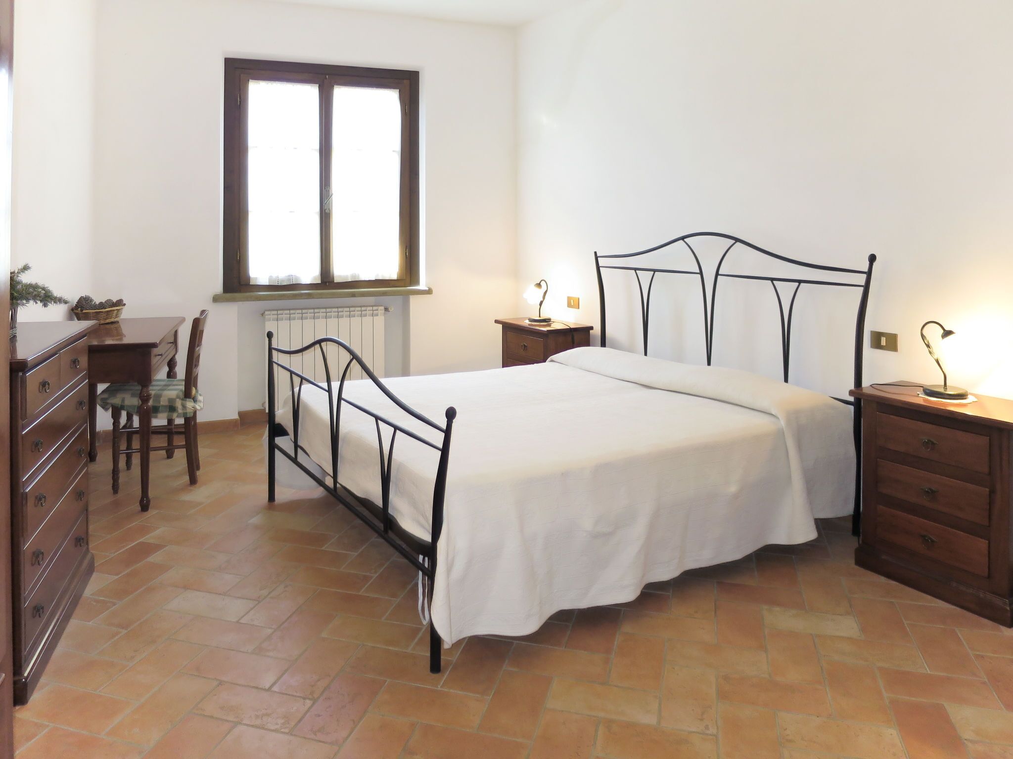 A bedroom with a bed, a desk, a chair, and a dresser.