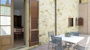 Une terrasse extérieure avec une table et des chaises, un mur en pierre et une porte en bois.
