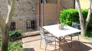 An outdoor patio with a table and chairs, a stone wall, and a metal railing. - Apartment Giada by Interhome (Pastina)
