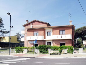 A two-story building with a brick facade, a pedestrian crossing sign, and a bench in front. - Casa Jolanda by Interhome (Rosolina Mare)