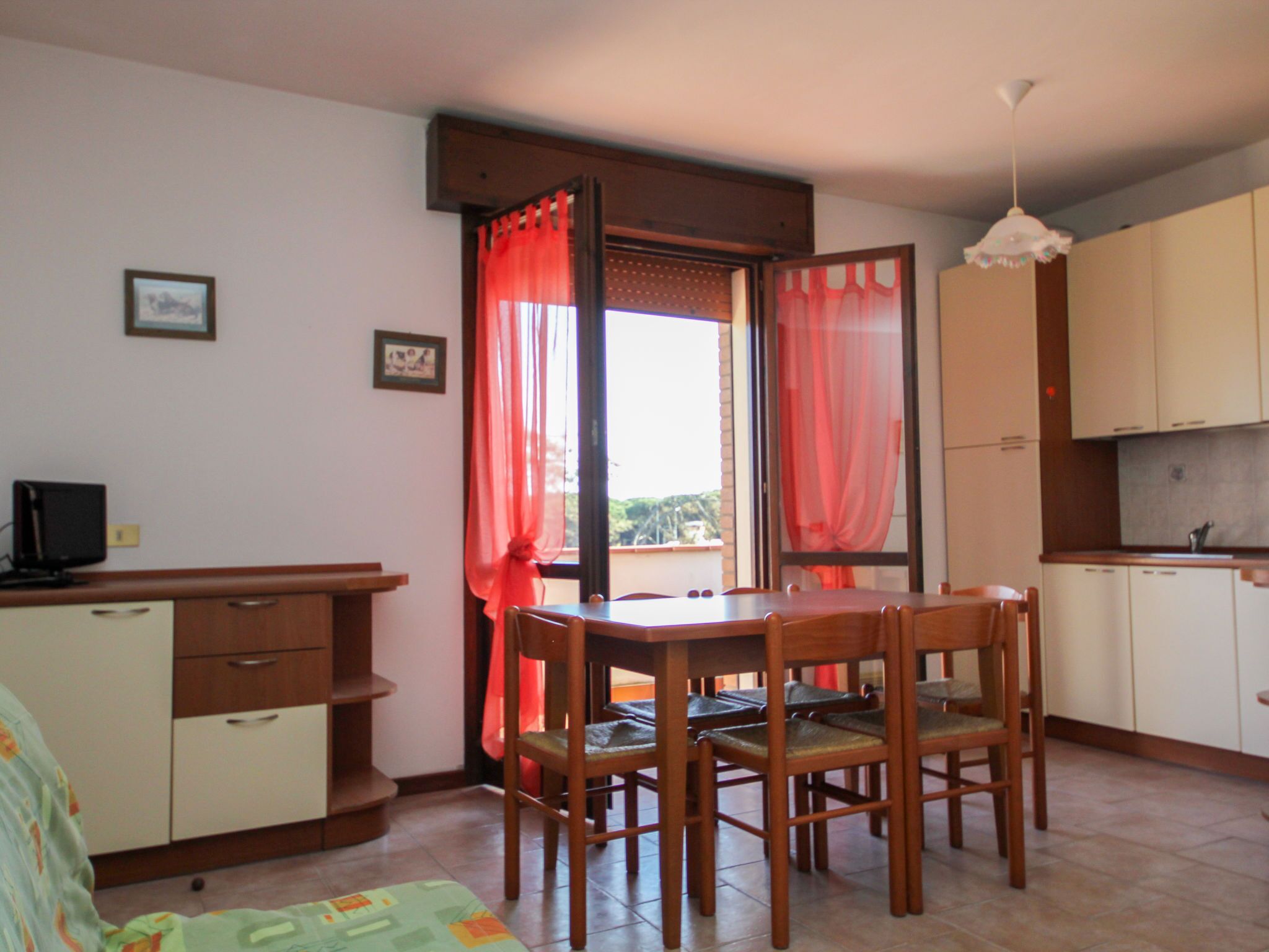 A compact kitchen with wooden cabinets and a dining table with chairs.