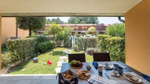 A patio with a table set for breakfast, including bread, fruit, and a newspaper. - Villaggio Tamerici by Interhome (Lignano Sabbiadoro)