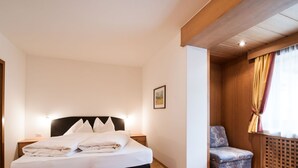 Een slaapkamer met een bed, nachtkastjes, een stoel en een raam met gordijnen.