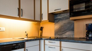 Een moderne keuken met witte kastjes, een zwarte magnetron en een koffiezetapparaat.
