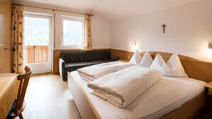 Una habitación de hotel con una cama, un sofá, una mesa de comedor y un ventanal con cortinas.