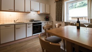 Una cocina moderna con armarios blancos, una mesa de comedor de madera y un ventanal con cortinas.
