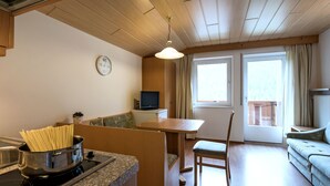 A compact kitchen with a stove, a sink, and a dining area with a table and chairs. - Ornella by Interhome (Santa Cristina)