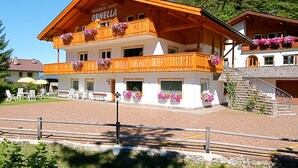 A two-story wooden building with balconies adorned with flowers, labeled "ORNELLA". - Ornella by Interhome (Santa Cristina)
