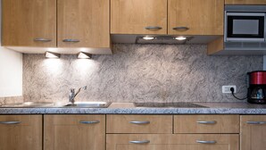 Una cocina con armarios de madera, encimeras de granito, un fregadero de acero inoxidable y una cafetera.