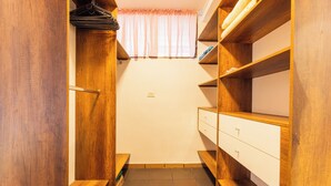 A narrow walk-through closet with wooden shelving and drawers.