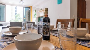 A dining table with bowls, glasses, and a bottle of wine.