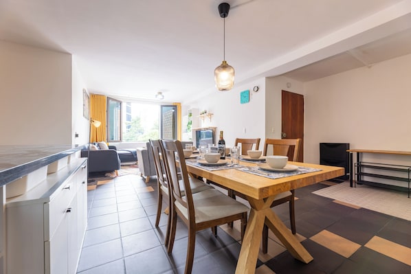 A modern kitchen with a dining table, chairs, and a hanging light fixture.