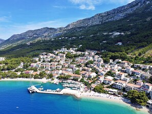 Une ville côtière avec des bâtiments construits sur une colline, un port de plaisance avec des bateaux et une plage.