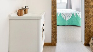 Une salle de bain moderne avec un meuble-lavabo blanc, un miroir à cadre doré et un panneau mural en bois.