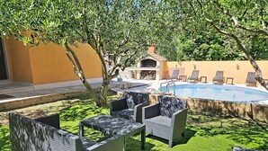 A poolside area with wicker furniture and a barbecue. - Vacation home Gorana by Interhome (Brač/Splitska)