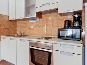 A modern kitchen with a built-in microwave, coffee maker, oven, and a sink.