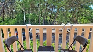 A wooden deck with two black chairs and a small table, surrounded by a white railing. - Vacation home Gorana by Interhome (Brač/Splitska)