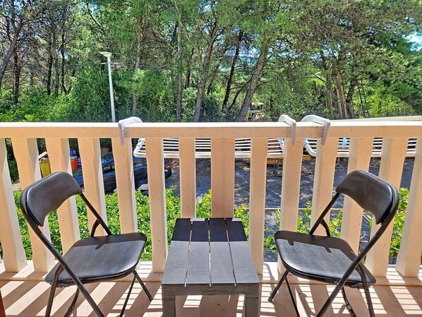 A wooden deck with two black chairs and a small table, surrounded by a white railing.